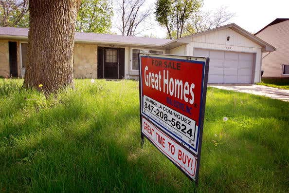 A home realtor sign in the front yard of a house