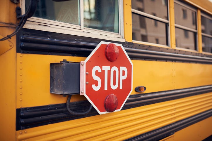 Side view of a school bus and its stop signal.