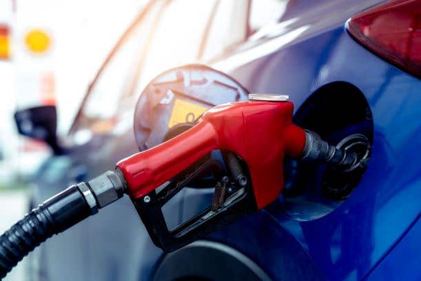 Red gas pump nozzle filling the tank of a blue car. Used in the story about Bad Gas in Lee County