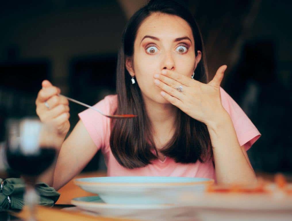 Lady feeling unwell after overeating in a restaurant (Caution: 6 Foods You May Want to Avoid at Restaurants)