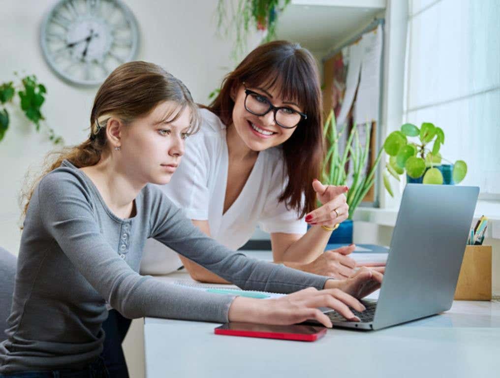 Mother and preteen daughter looking i laptop together, girl typing on keyboard (Stranger Danger 2.0: What Parents Need to Know)