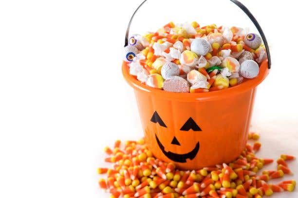 orange pumpkin bucket full of candy corn and other sweets