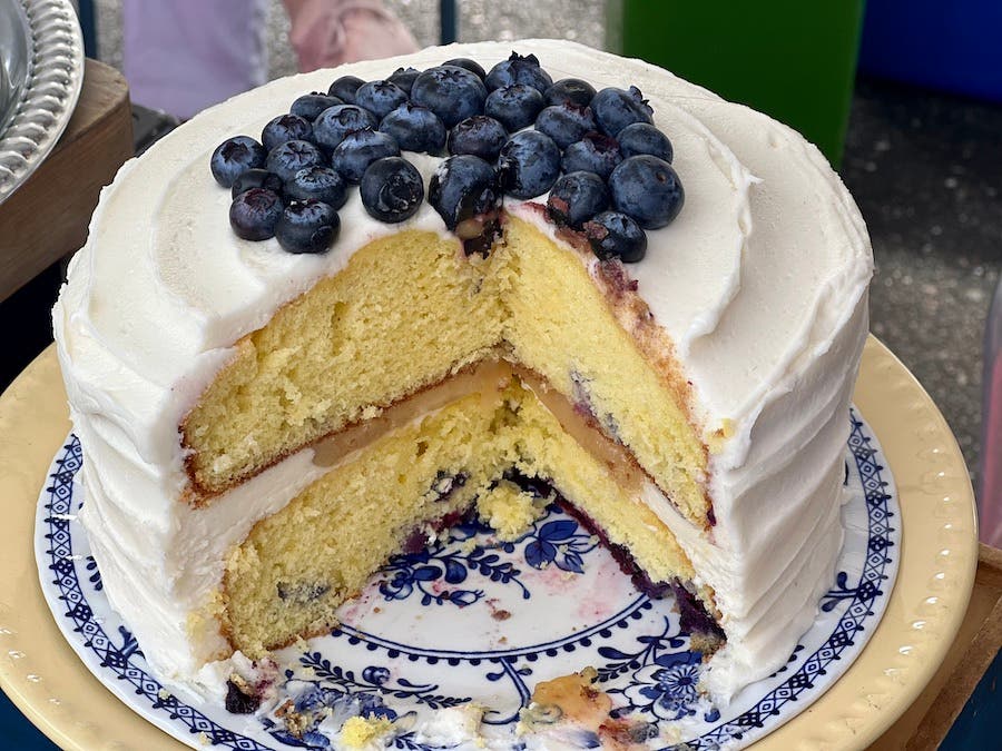 white cake topped with blueberries, with a big slice taken out so you can see the inside layers.