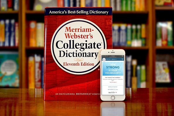 Merriam-Webster dictionary placed on a table next to a phone