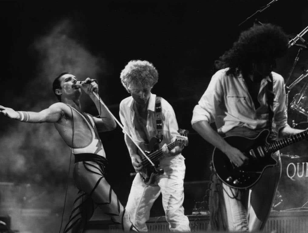 Queen in concert, from left to right; Freddie Mercury (Frederick Bulsara, 1946 - 1991), John Deacon, and Brian May.