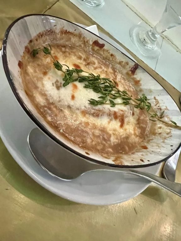 a bowl of soup topped with melted cheese and a sprig of herbs. Fun Happenings In SWFL This Weekend