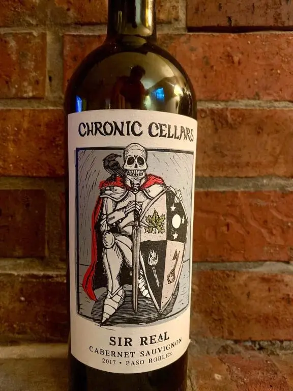 Bottle of Chronic Cellars Sir Real Cabernet agains a red brick wall