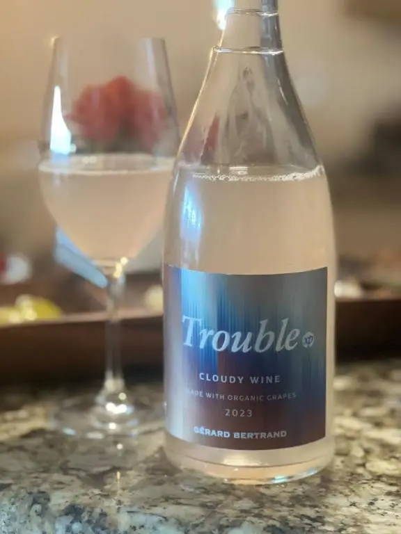 Bottle of Trouble wine with a glass of it in the background