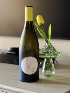 Bottle of Lucy Pinot Blanco with a yellow flower in a vase