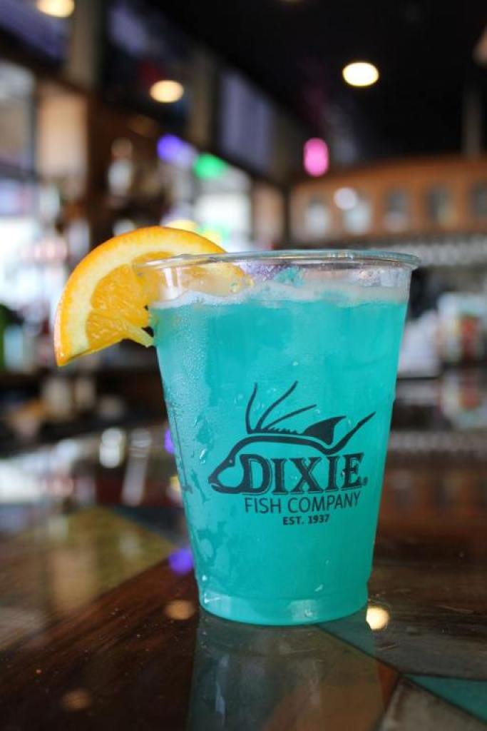 A blue cocktail in a glass with a lemon wedge for a garnish