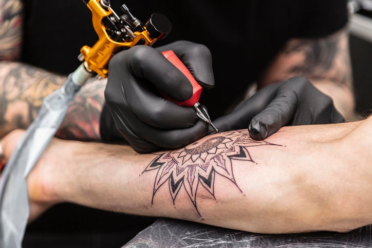 Process of creating tattoo in form of black flower. Master does work in sterile gloves, a Southwest Florida Weekend event