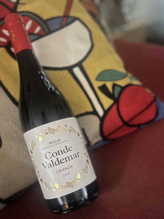 Bottle of Bodegas Valdemar 2019 Conde Valdemar Crianza on a red couch