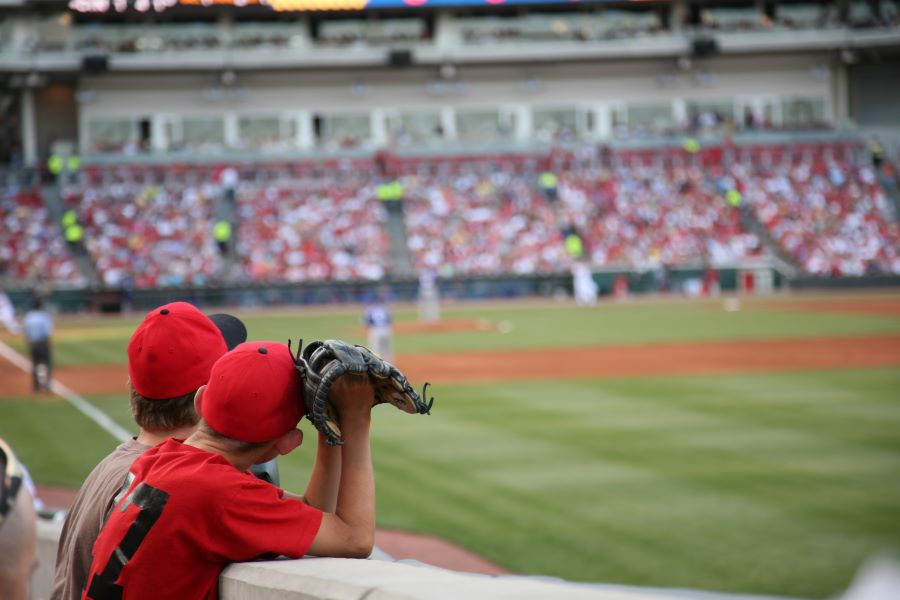 two young boys with catchers mits, leaning over the wall at a baseball stadium, watching the players, a Southwest Florida Labor Day Weekend events